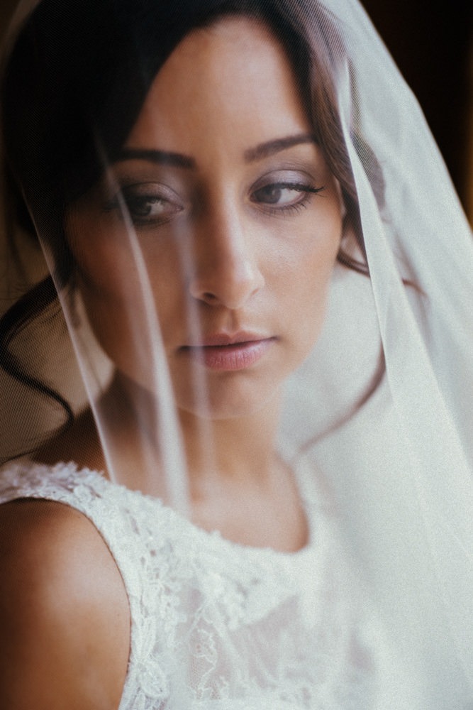 Portrait einer italienischen Braut. Sie schaut verträumt unter ihrem Schleier hervor.